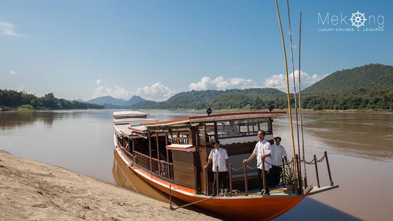 Crew welcoming guests aboard a Mekong River Cruise Laos boat docking riverside