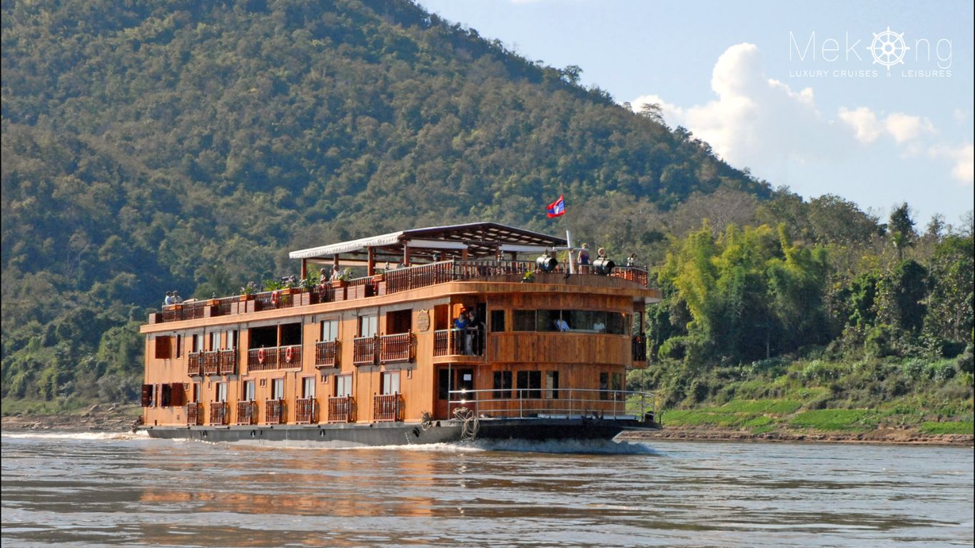 A Mekong River Cruise Laos deluxe boat sailing past green hills