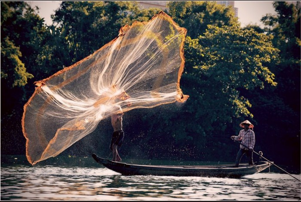 A fisherman is trying to hit the net as far as possible to catch much more fish