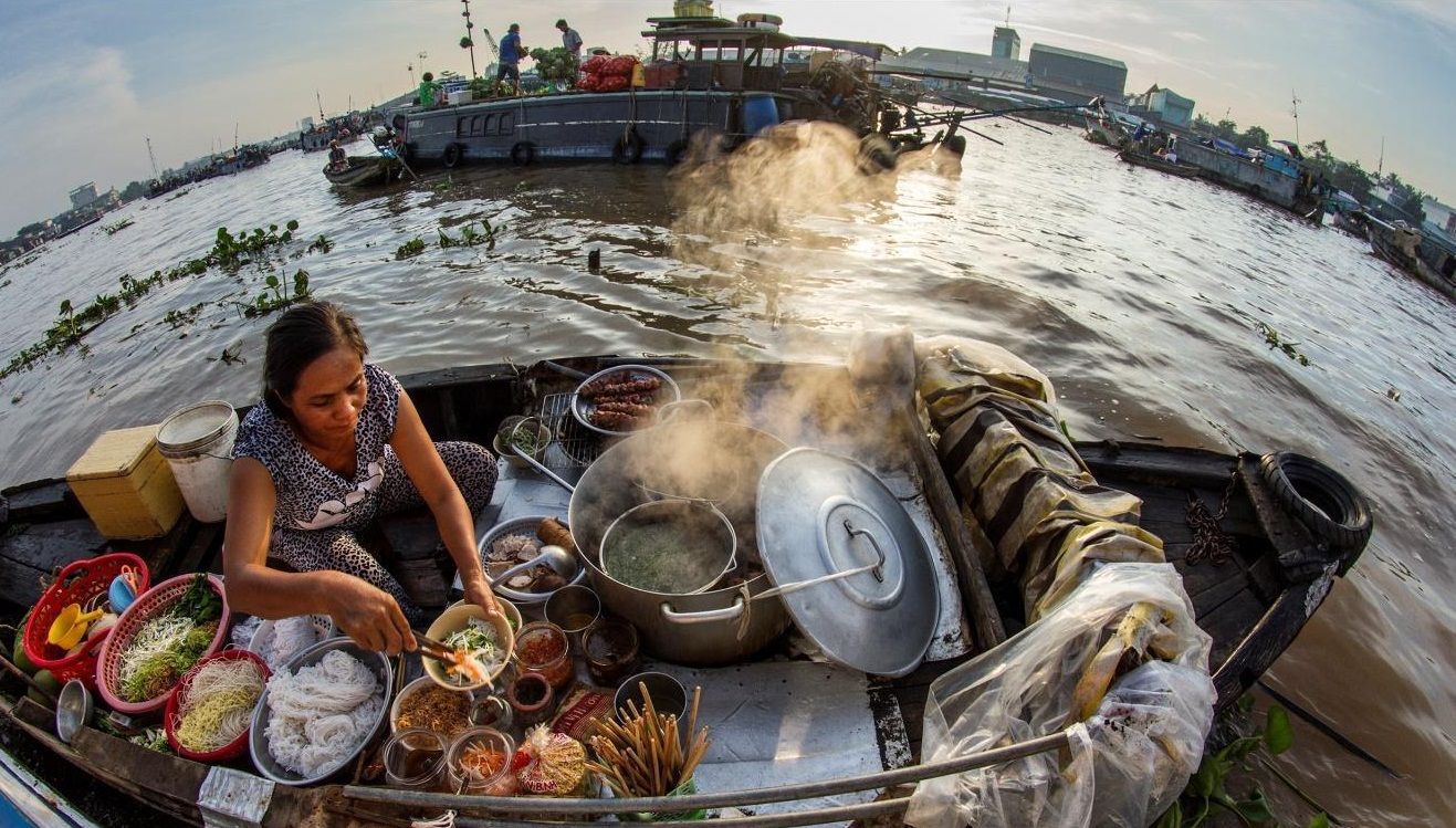 An old lady is selling Vietnamese traditional noodles on her own boat