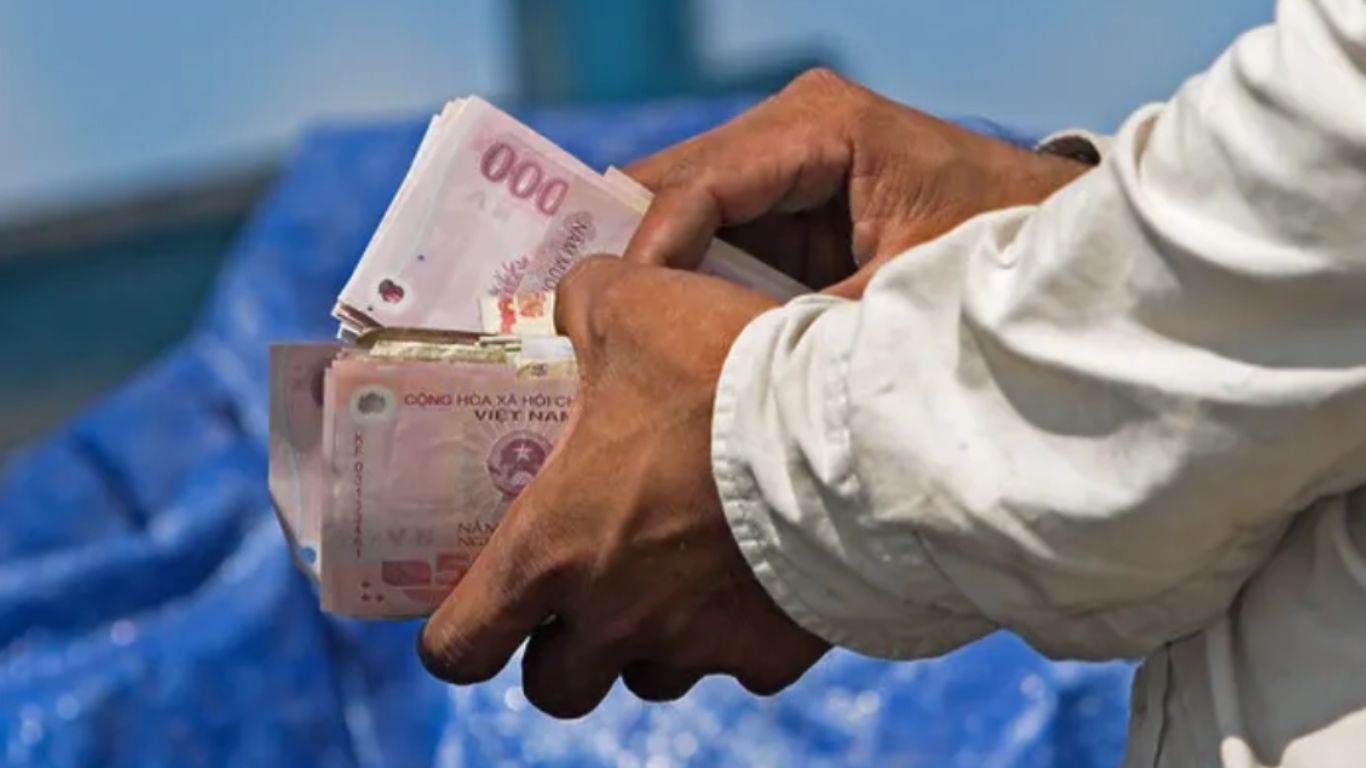 Person holding a stack of Vietnamese cash at Cai Rang Floating Market